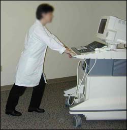 Sonographer using proper body mechanics to move ultrasound equipment.
