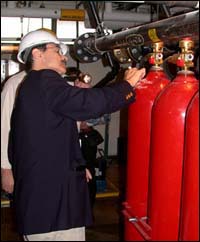 Fire extinguishing system specialist inspecting high pressure CO2 system on vessel.