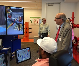 Dr. Michaels observes a demonstration of an oil rig drilling operations simulator.