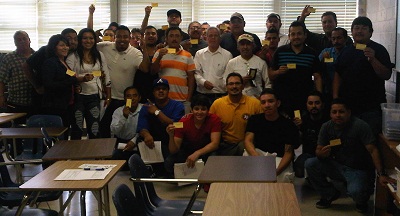Employees proudly showing their OSHA 10 cards with trainer and OSHA representative, Mark A. Hernandez (in yellow shirt)