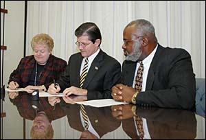 (seated left to right) BSCAI Executive Vice President, Carol A. Dean and OSHA's then-Assistant Secretary, John Henshaw, sign national Alliance on December 2, 2004 as BSCAI President, LeRoy Dock looks on.