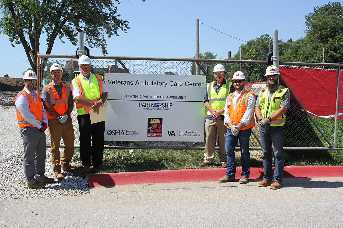 (standing left to right): Ryan Sawall, Project Director, McCarthy Construction Companies;  Steve Miller, Divisional Safety Director, McCarthy Construction Companies, Darwin Craig, Assistant Area Director, Omaha Area Office, US DOL-OSHA, Jeff Funke, Area Director, Omaha Area Office, US DOL-OSHA, Kris Montgomery, Project Manager, McCarthy Construction Companies; and Andy Parrish, Assistant Project Safety Manager, McCarthy Construction Companies after the signing ceremony.
