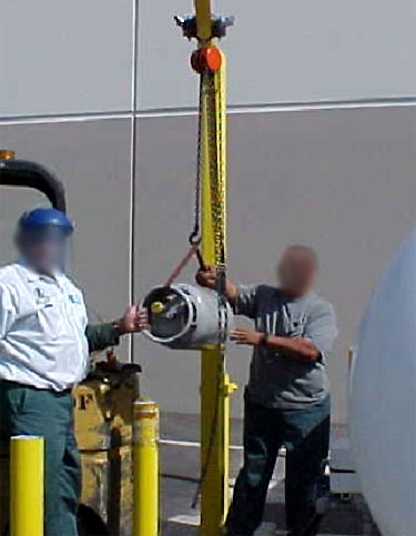 Workers using a chain hoist to lift a 10 gallon liquid propane tank