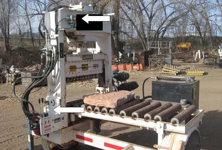Retrofitted stone cutter with arrows showing top control button (added in the retrofit) and bottom controls (existing hand controls). The operator must press both the button and one of the hand controls to lower the blade.