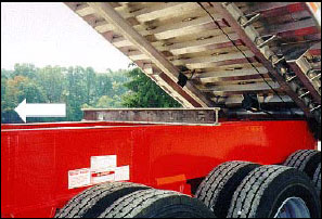 Figure 3. Shows a steel I-beam makeshift body prop: steel I-beam sits across truck frame. The I-beam is not attached to the truck frame or dump body. The I-beam could be displaced in the direction of the arrow by the inadvertent movement of the dump body or truck frame.